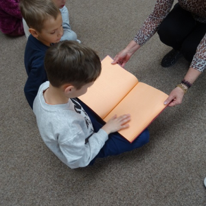 Chłopiec dotyka strony książki pisanej w  języku Breill'a.