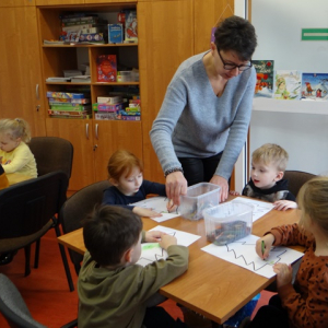 Bibliotekarka ogląda rysunki dzieci.