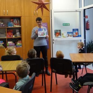 Bibliotekarka pokazuje dzieciom książkę.