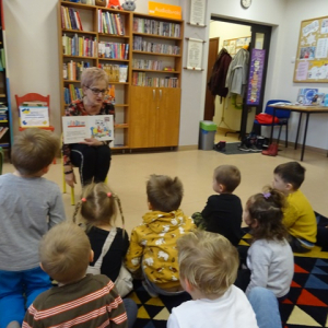 Bibliotekarka czyta i pokazuje dzieciom książkę o Kici Koci.