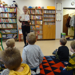 Bibliotekarka pokazuje dzieciom zniszczoną - smutną książkę.