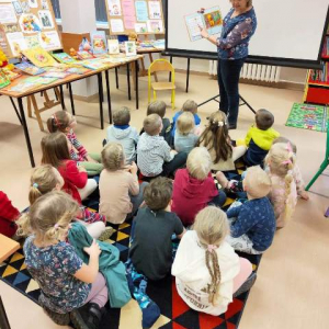 Bibliotekarka czyta przedszkolakom opowiadanie o Kubusiu Puchatku.