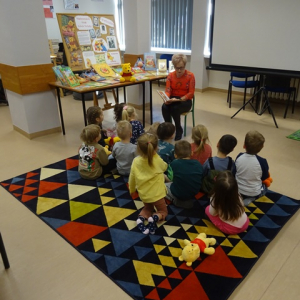 Bibliotekarka czyta dzieciom bajkę o Kubusiu Puchatku.