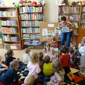 Bibliotekarka pokazuje przedszkolakom kolorową ilustrację. 