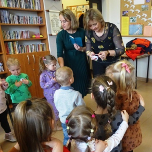 Bibliotekarka przykleja dzieciom pamiętkowe medale.