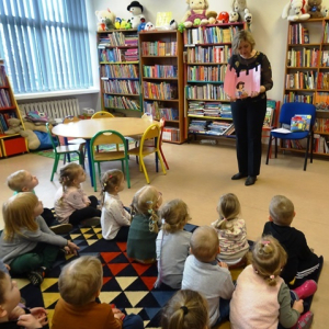 Bibliotekarka pokazuje dzieciom książkę .