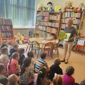 Bibliotekarka pokazuje przedszkolakom kolorową książeczkę.