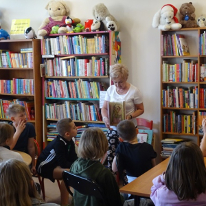 Bibliotekarka pokazuje uczniom książkę.