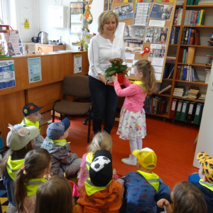 Dziewczynka wręcza bibliotekarce kwiatek.