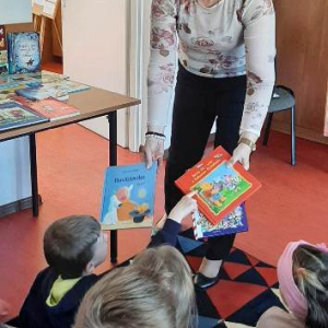 Bibliotekarka rozdaje przedszkolakom książki.