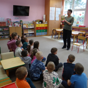 Bibliotekarka pokazuje przedszkolakom okładkę książki..