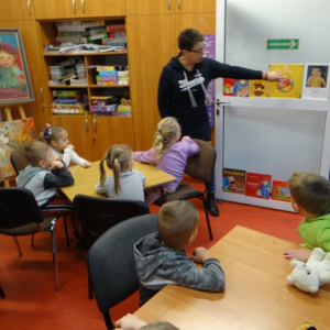 Bibliotekarka pokazuje dzieciom bajeczki o niedżwiadkach.