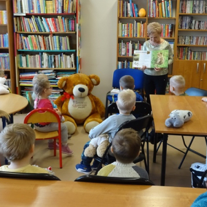 Bibliotekarka pokazuje dzieciom obrazki z książeczki.