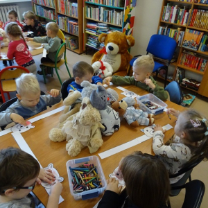 Przedszkolaki kolorują opaski na głowę z misiami.