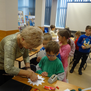 Bibliotekarka przykleja z dziećmi słoneczka do patyków