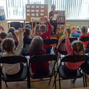 Bibliotekarka czyta dzieciom zagadki o wiośnie