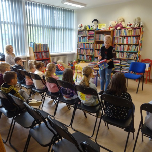 Bibliotekarka pokazuje uczniom książkę z materiału.