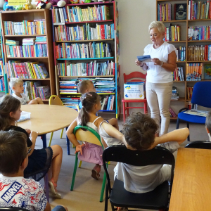 Bibliotekarka pokazuje dzieciom widokówki i czyta przysłane pozdrowienia.