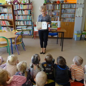 Bibliotekarka pokazuje dzieciom zniszczoną książkę.