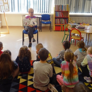 Bibliotekarka pokazuje dzieciom ilustracje w książce