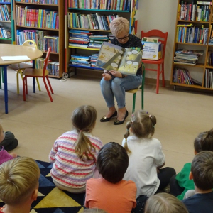 Bibliotekarka czyta i pokazuje dzieciom ilustracje