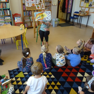 Bibliotekarka pokazuje przedszkolakom ilustracje w książki