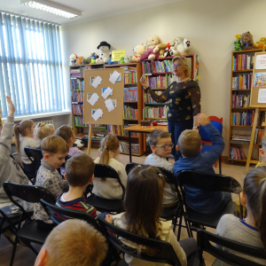 Bibliotekarka pokazuje dzieciom łupinkę orzecha.
