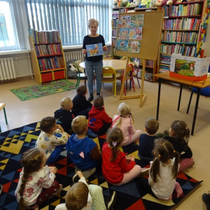 Bibliotekarka pokazuje przedszkolakom ilustracje z bajki