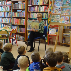 Bibliotekarka czyta dzieciom bajkę i pokazuje ilustracje