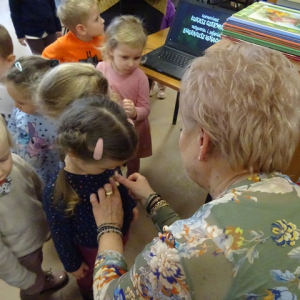 Bibliotekarka przykleja przedszkolakom misie