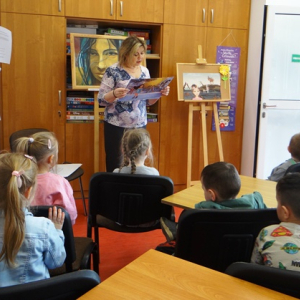Bibliotekarka czyta przedszkolakom bajkę z teatrzyku "Kamishibai"