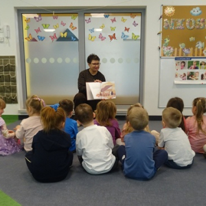Bibliotekarka czyta przedszkolakom bajkę i pokazuje ilustracje z książki