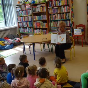 Dzieci słuchają opowiadania i oglądają ilustracje w książce