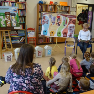 Bibliotekarka czyta dzieciom opowiadanie o segergowaniu śmieci.