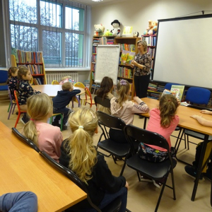 Bibliotekarka pokazuje dzieciom książkę. 